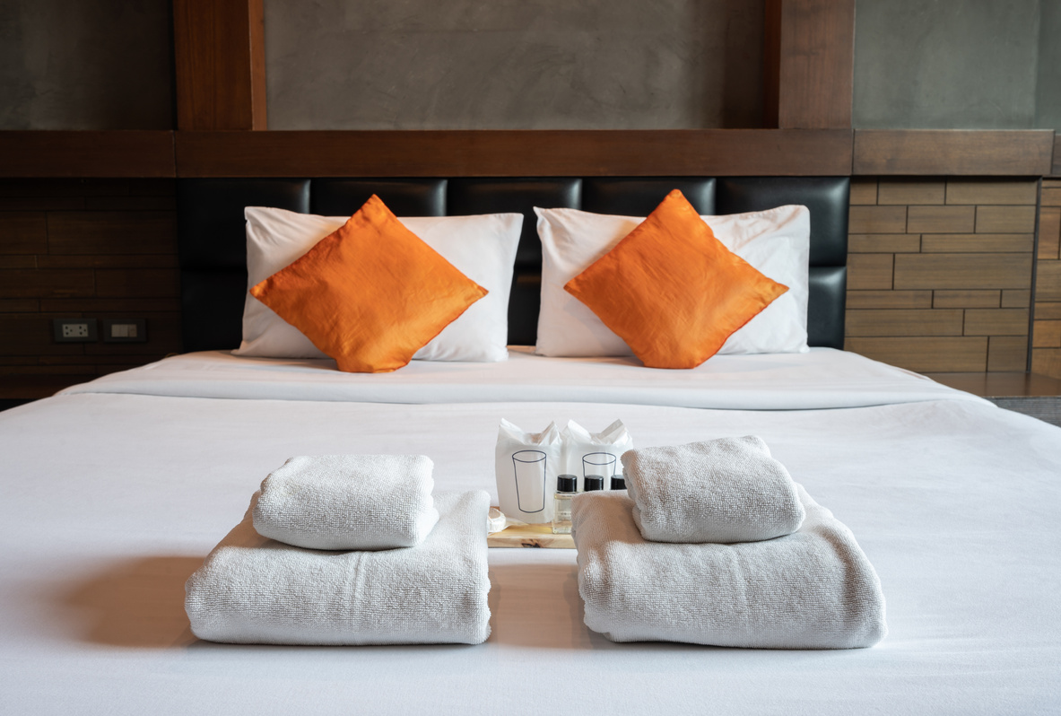 Set of hotel amenities (such as towels, shampoo, soap etc.) on the bed in hotel bedroom.